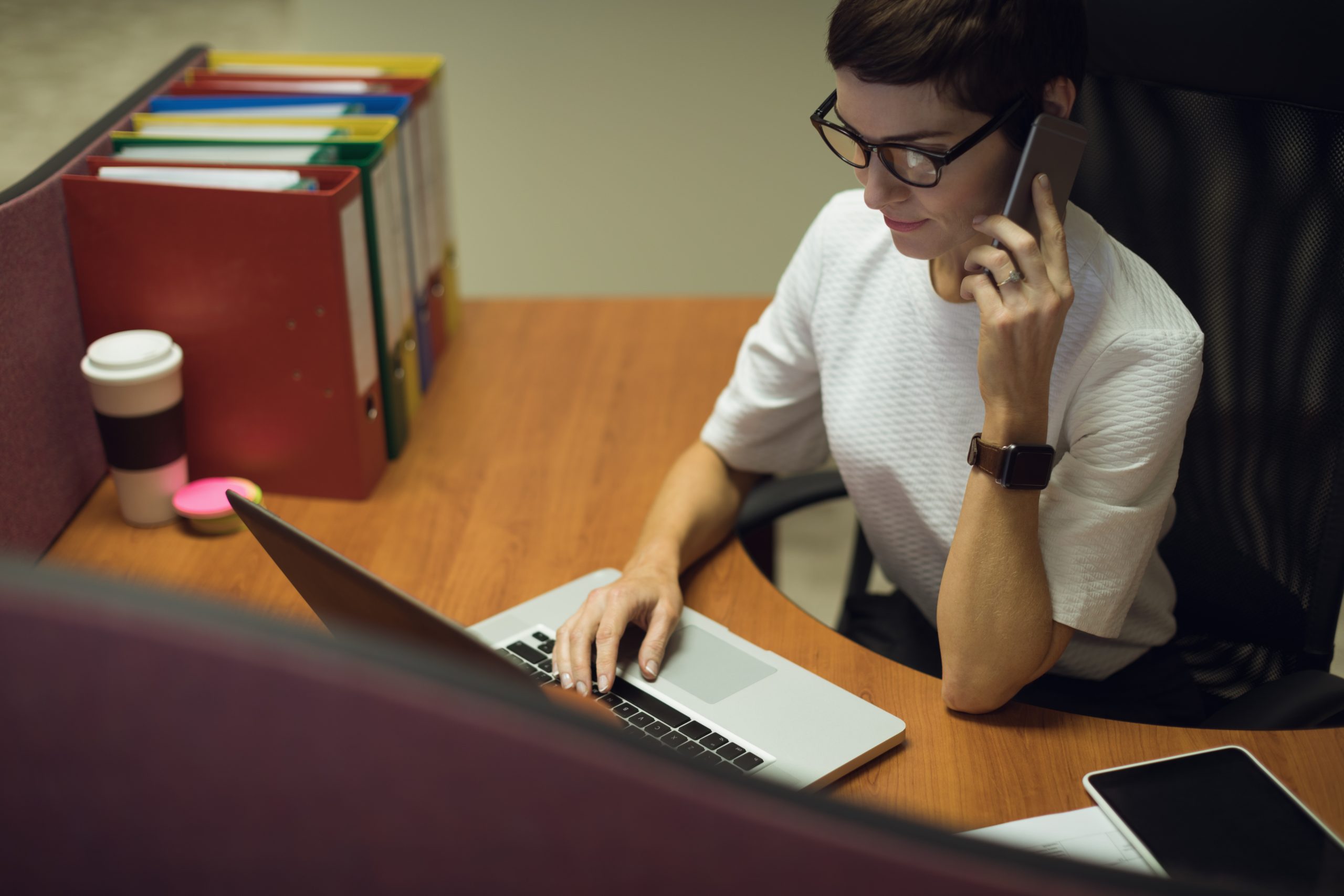 Professora com smartphone e notebook representando o conceito de Telefonia VoIP para Escolas e Universidades